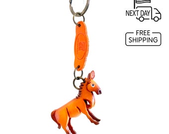 May include: A brown leather keychain with a small, detailed horse figurine. The keychain has a metal ring and a leather tag with the text "The Leather Key".