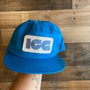 May include: A blue baseball cap with a white patch that says "ICG" in a retro, stylized font.