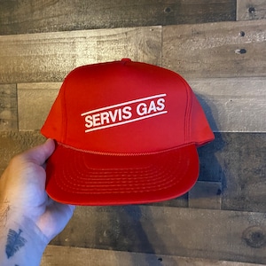 Puede incluir: Una gorra de camionero roja con un logotipo bordado en blanco que dice "SERVIS GAS" en un rectángulo.