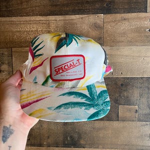May include: White baseball cap with a tropical print and a red patch that says "SPECIAL-T MILLING CO RIO RANCHO NM"