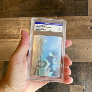 May include: A graded 1995 Upper Deck Jerome Bettis #P86 hologram trading card. The card is encased in a clear plastic holder with the text "GRADEMYCARDS.com" and a grade of "9 MINT". The card features a holographic image of a football player.