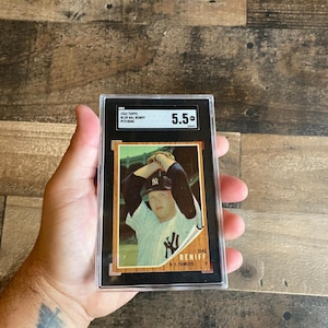 Könnte beinhalten: Eine bewertete Baseballkarte von Hal Reniff von den New York Yankees. Die Karte befindet sich in einem schwarzen Halter, bewertet mit 5,5. Die Karte zeigt Reniff in seiner Yankees-Uniform mit dem Teamlogo. Die Karte stammt aus dem 1962 Topps-Set.