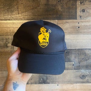 May include: Black baseball cap with a yellow embroidered logo of a man holding a pickaxe and the text "Fosdick Benefit".