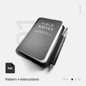 Puede incluir: Una cubierta de cuaderno de cuero negro con un portaplumas. La cubierta está diseñada para adaptarse a un cuaderno de notas Field Notes de 48 páginas. La cubierta tiene las palabras "FIELD NOTES" y "48-Page Memo Book" impresas en ella. La cubierta está hecha en los EE. UU.