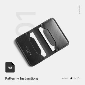 May include: Black leather card holder with a minimalist design. The card holder has two slots for cards and the text "DARKSAILS PARIS" is embossed on the front.