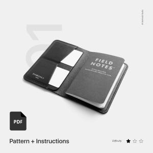 Può includere: Una copertina per taccuino in pelle nera con una tasca per carte e un taccuino Field Notes all'interno. La copertina ha il testo "DARKSAILS" stampato su di essa. Il taccuino ha il testo "FIELD NOTES" stampato su di esso. L'immagine include il testo "PDF Pattern + Instructions" e "Difficulty".