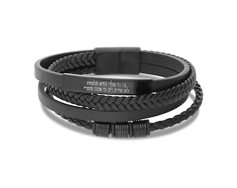 May include: Black leather bracelet with a braided design and a metal clasp. The bracelet has a metal plate with Hebrew text engraved on it.
