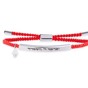 Könnte beinhalten: Ein Armband aus roter geflochtener Kordel mit einer gebogenen, silberfarbenen Metallstange, die mit hebräischem Text graviert ist. Das Armband enthält einen kleinen silberfarbenen Hamsa-Hand-Anhänger und einen verschiebbaren Metallverschluss.