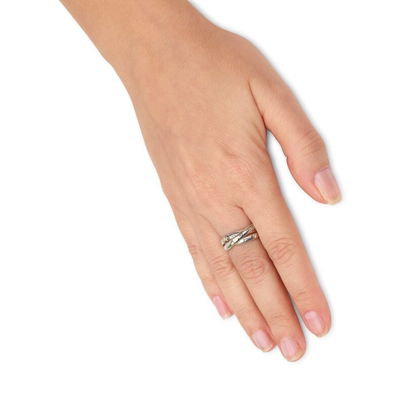 May include: A silver ring with a unique interwoven design. The ring is worn on the middle finger of a hand.