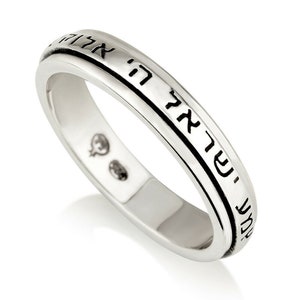 May include: A silver ring with a Hebrew inscription around the band. The inscription reads "Shema Yisrael Adonai Eloheinu Adonai Echad" which translates to "Hear O Israel, the Lord our God, the Lord is One."