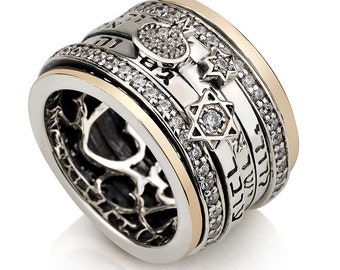 May include: A silver and gold spinning ring with a Star of David, a heart, and Hebrew writing. The ring is set with clear cubic zirconia stones.