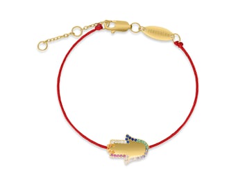 May include: A red string bracelet with a gold hamsa charm. The hamsa charm is decorated with colorful gemstones.