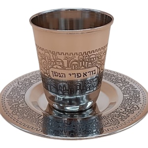 Pode incluir: Uma taça de Kiddush de prata e um prato a condizer com um desenho gravado da cidade de Jerusalém em hebraico. A taça tem as palavras hebraicas "ירושלים" (Jerusalém) e "עיר הקודש" (Cidade Santa) gravadas nela.