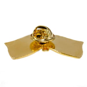 May include: Gold-colored metal pin with a butterfly design. The pin has a safety clasp on the back.