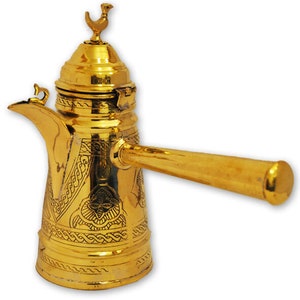 Könnte beinhalten: Eine goldfarbene Kaffeekanne aus Metall mit aufwendigen Gravuren. Die Kanne hat einen langen Griff und einen kleinen Vogel als Knauf auf dem Deckel.