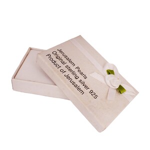 Pu&ograve; includere: Una scatola regalo bianca con un nastro bianco e un fiocco verde. La scatola &egrave; aperta e l'interno &egrave; vuoto. Sulla scatola &egrave; stampato il testo "Jerusalem Pearls Original sterling silver 925 Product of Jerusalem".