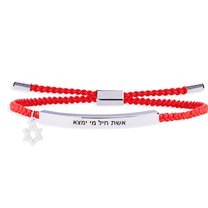 May include: Red braided bracelet with a silver bar and a Star of David charm. The silver bar has Hebrew text. The bracelet has a sliding clasp for adjustable sizing.
