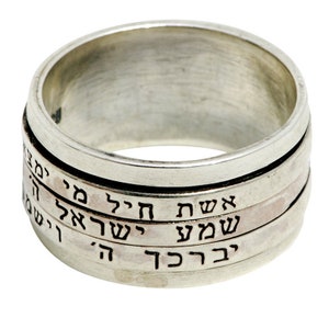 May include: A silver spinning ring with Hebrew text engraved on each band. The text reads "בַּרְכָּת" "שָׁלוֹם" "אֱמֶת" "הַקֹּל"
