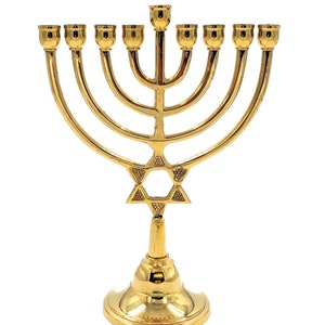 Può includere: Un candelabro dorato con un designo a stella di David. Il candelabro ha nove portacandele e una base con la parte superiore rotonda.