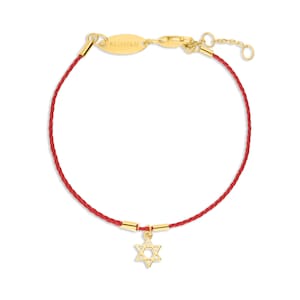Pode incluir: Pulseira de corda vermelha com um amuleto de ouro em forma de Estrela de David. A pulseira tem um fecho de ouro e uma pequena etiqueta de ouro que diz "IL  FOCOLARE".
