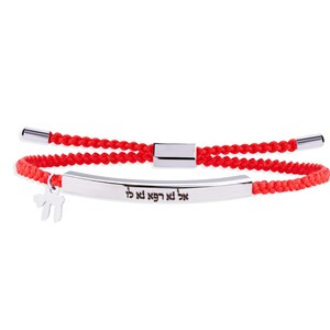 May include: Red braided bracelet with a silver bar and a small charm. The silver bar has Hebrew text. The bracelet has a sliding clasp for adjustable sizing. The charm is a stylized symbol.