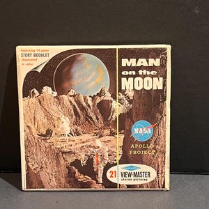 May include: Vintage View-Master reel set titled "Man on the Moon" featuring 21 stereo pictures. The cover displays an illustration of an astronaut on the moon with a lunar lander, a planet, and the NASA logo. Includes a 16-page story booklet.