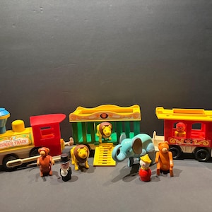May include: A vintage Fisher-Price Circus Train toy set featuring a red and yellow locomotive with the text Circus Train, a green animal cage car, and a red passenger car. Includes plastic animal figures like a lion, elephant, and bear.