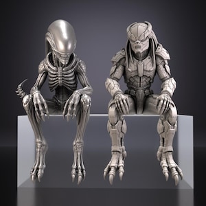 May include: Two silver-toned figurines depicting a Xenomorph and a Predator, both in a seated position. The Xenomorph features an elongated head and ribbed torso, while the Predator displays intricate armour plating and a distinct facial mask.