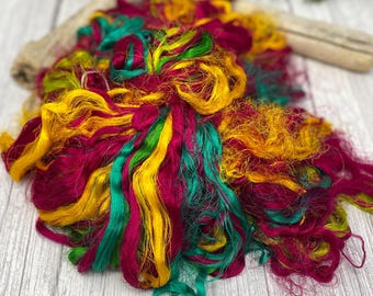 May include: A pile of colorful yarn in shades of red, yellow, and green. The yarn is soft and fluffy, and it would be perfect for knitting or crocheting.