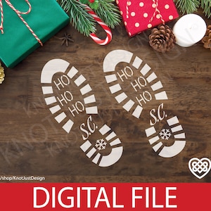 May include: Two white footprints on a brown wooden surface. The footprints have the words "HO HO HO" and "S.C." written on them. The footprints are surrounded by Christmas decorations, including a red and white candy cane, a red gift box with white polka dots, a green gift box with a white bow, and pine branches.