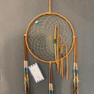 May include: A brown dreamcatcher with a white web and turquoise beads. It has brown leather straps and feathers with turquoise and white beads.