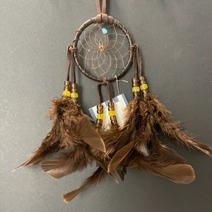 May include: A brown dream catcher with yellow and blue beads and brown feathers.