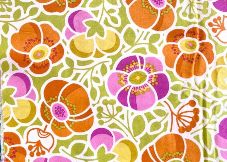 May include: A fabric with a repeating pattern of stylized flowers in shades of orange, pink, and yellow on a green background.