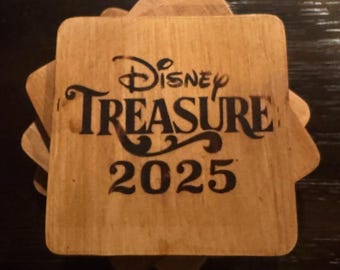 Könnte beinhalten: Ein Satz aus vier Holz-Untersetzern mit brauner Holzoptik. Die Untersetzer haben ein schwarz-weißes Design mit dem Text "Disney Treasure 2025".