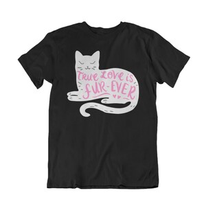May include: Black t-shirt featuring a white cat illustration with the text "True love is fur-ever" in pink. The cat design includes a tail and small hearts. The shirt is a classic crew neck style.
