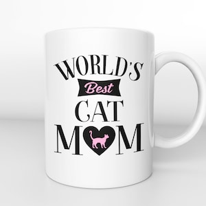 May include: White ceramic mug with black text that reads "WORLD'S Best CAT MOM" with a pink cat silhouette inside a black heart.