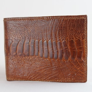 May include: A brown leather wallet with a textured ostrich skin pattern.