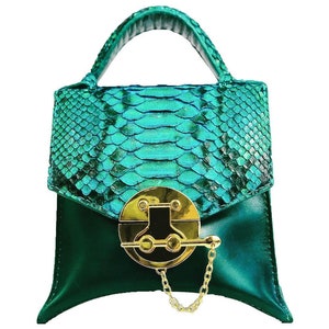May include: A small, emerald green handbag with a top handle and a gold clasp. The bag is made of snakeskin and has a unique, textured design.