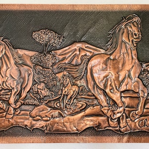 May include: Copper relief artwork showing a herd of horses galloping across a landscape with mountains and trees. The word "Chile" is inscribed. The artwork has a dark background and a copper-coloured frame.