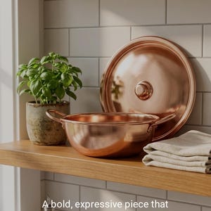 May include: Copper cookware set with a matching lid, displayed on a wooden shelf. The set includes a bowl and a lid, reflecting a warm, metallic hue. A potted plant and a folded cloth are also on the shelf. Text reads: ELEVATE YOUR KITCHEN DECOR.