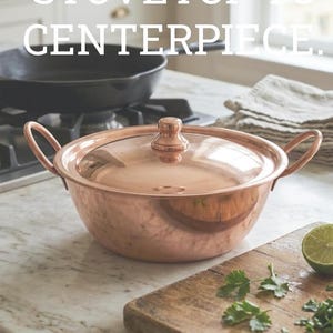 May include: A copper pot with a glass lid and handles sits on a marble countertop. The pot is next to a black cast iron pan on a stovetop. Text reads: "FROM STOVETOP TO CENTERPIECE."