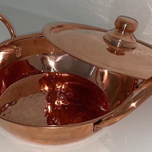 May include: A hammered copper serving bowl with a lid. The bowl has two handles and the lid has a knob on top.