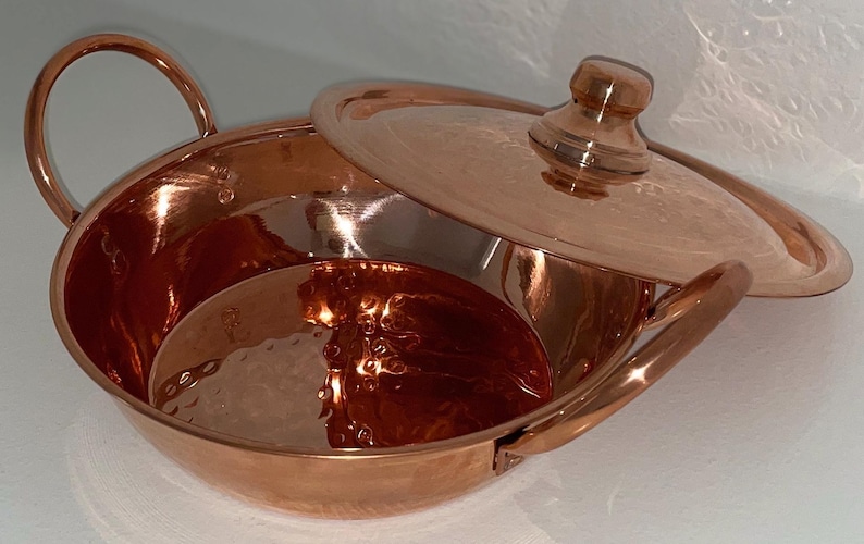 May include: A hammered copper serving bowl with a lid. The bowl has two handles and the lid has a knob on top.