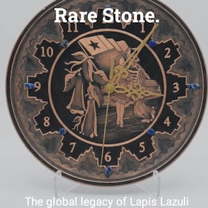 Pode incluir: Um relógio redondo com moldura cor de cobre e mostrador preto. O relógio apresenta uma ilustração detalhada com uma bandeira e uma mulher. O texto "Two Countries. One Rare Stone" está no topo. Os ponteiros do relógio são dourados.