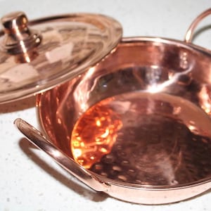 May include: A copper serving dish with a lid and two handles. The dish has a hammered finish and is perfect for serving small dishes.