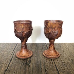 Puede incluir: Dos copas de cerámica marrón con superficies texturizadas y un diseño orgánico único. Las copas tienen un tallo y una base ancha, perfectas para servir bebidas. El diseño presenta un patrón texturizado en relieve alrededor del cuenco.
