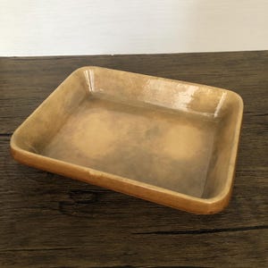 Op de afbeelding: Een rechthoekige keramische ovenschaal met afgeronde hoeken. De schaal heeft een lichtbruine buitenkant en een lichtere binnenkant. De randen zijn iets donkerder, wat een subtiel contrast creëert. De schaal is leeg en staat op een donker houten oppervlak.