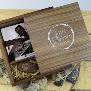 May include: A wooden box with a sliding lid. The lid has a white logo that says "Matt Wilkinson Photography". The box is open and contains a USB drive and a stack of photo prints.