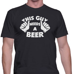 May include: Black t-shirt with white text that reads "This Guy Needs A Beer" with two thumbs up on either side of the text.