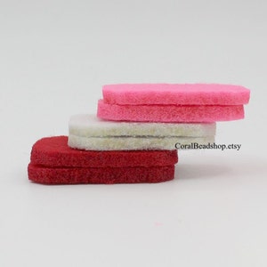 May include: A stack of six flat, rectangular felt pieces arranged in three colour-coded pairs. The top pair is bright pink, the middle pair is off-white, and the bottom pair is deep red. The text CoralBeadshop.etsy is visible on the side.